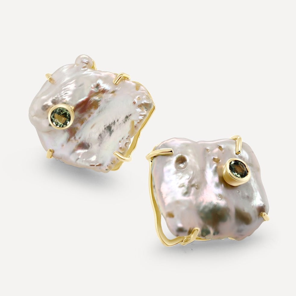 Sizeable baroque pearls embellished with bezel set blue sapphires. Wear these earrings and make a head turning statement. Perfect for a daily assortment.  Estimated Coloured Stone Weight: 0.28 Carat of Sapphire Gold Weight: 18K Yellow Gold